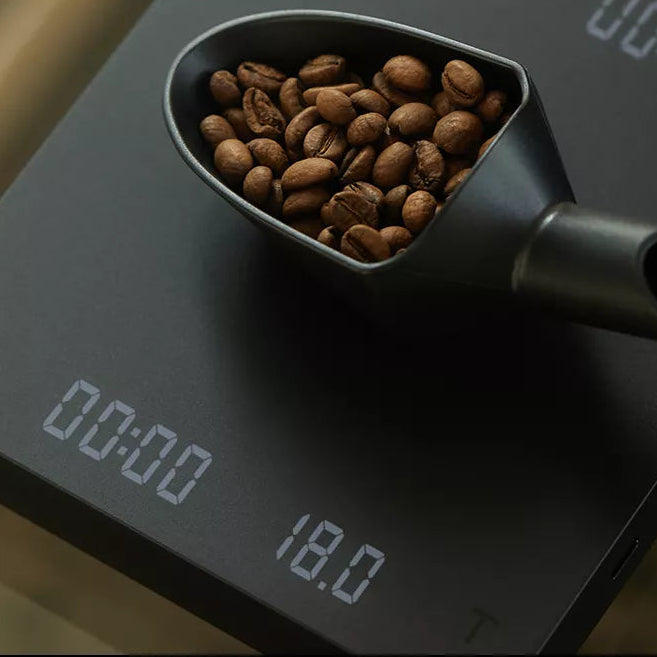 Digital scale with a cup of coffee beans on a blurred background