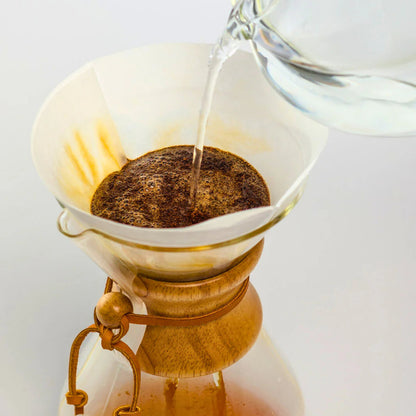 Pouring hot water in a glass coffee maker on a white background