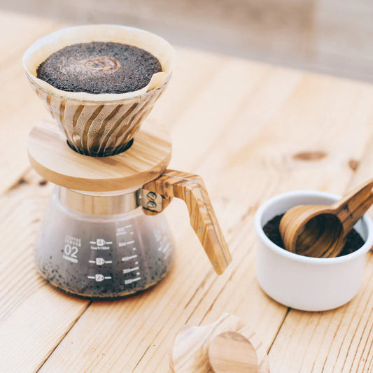 Coffee brewing setup with a pour-over coffee maker on a wooden surface.