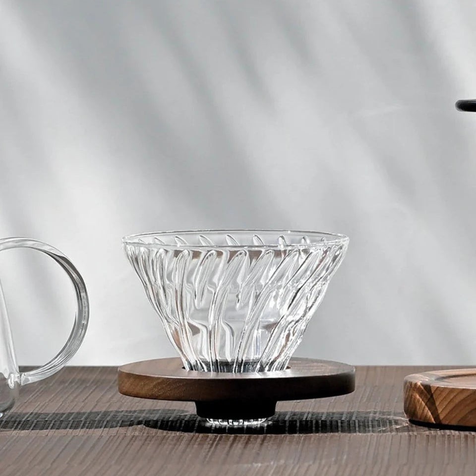 Clear glass coffee dripper on a wooden stand with a blurred background